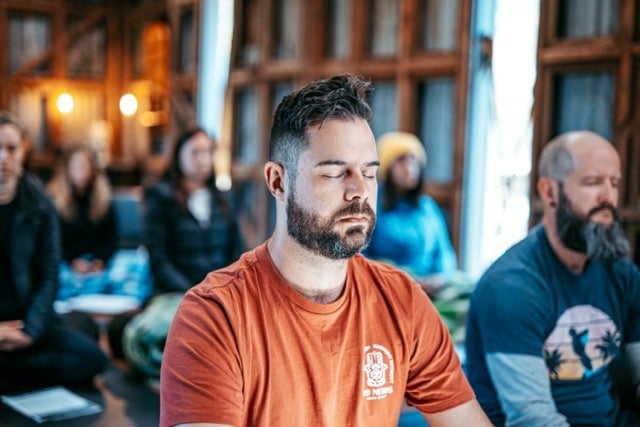 A group of people sitting on the floor practising nasal breathing.