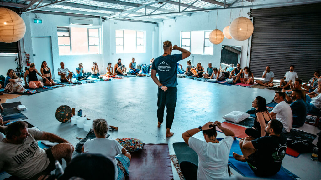 A group of people studying to become breathwork facilitators sitting in a circle.